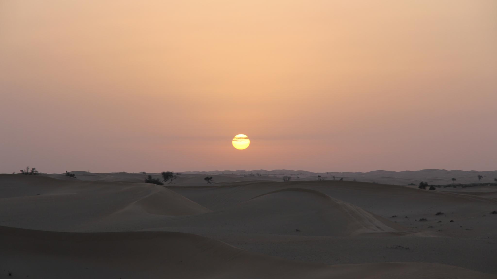 Sonnenaufgang vor einer hügeligen, kargen Landschaft im frühmorgendlichen Licht