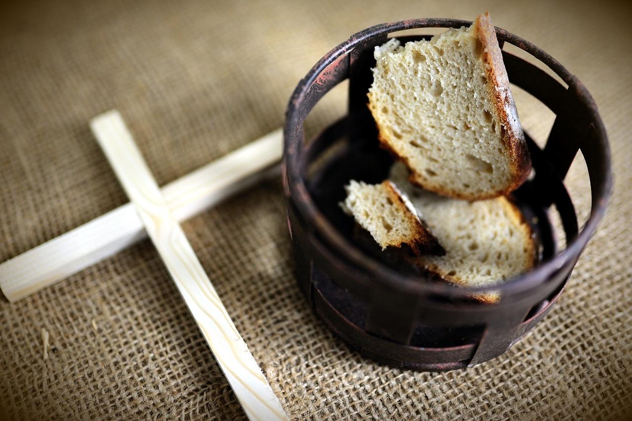 Fastenzeit Symbol - ein schlichtes Kreuz aus Holz, ein Korb mit Brot