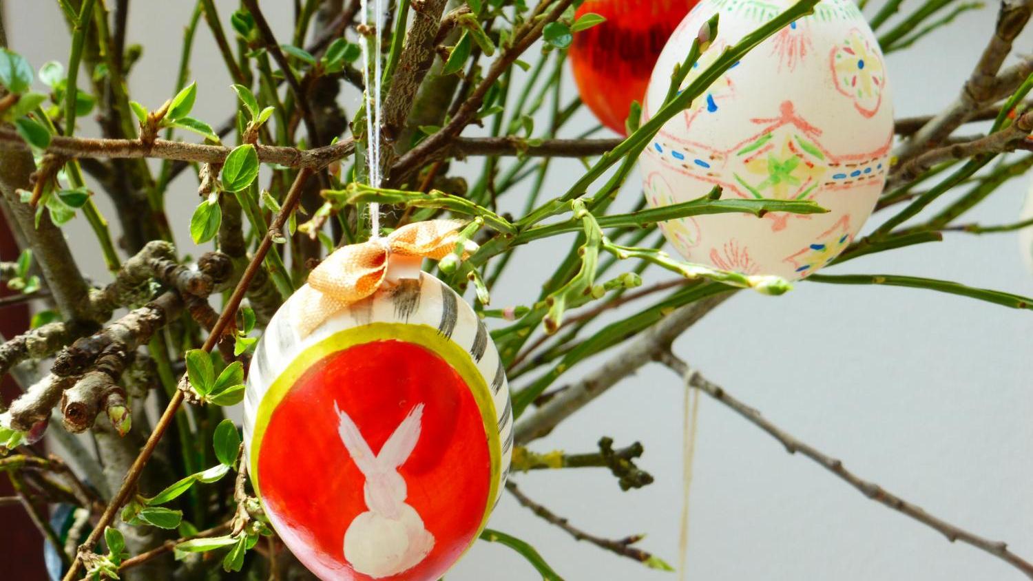 Ein Osterstrauch, an dem drei bemalte Ostereier hängen