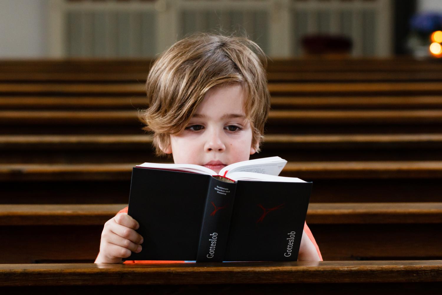Kind mit Gebetbuch in einer Kirchenbank