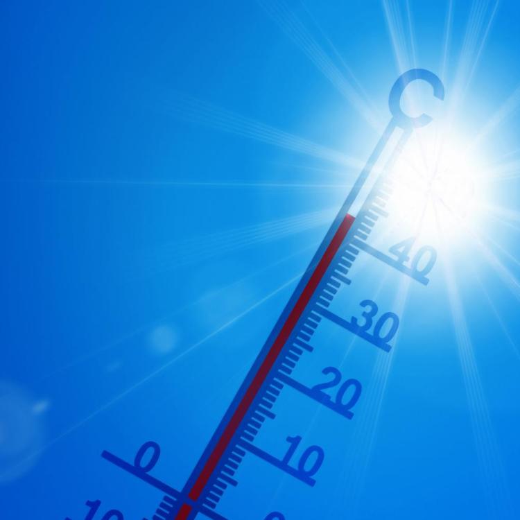 Thermometer vor brütend, heißer Sonne und blauem Himmel