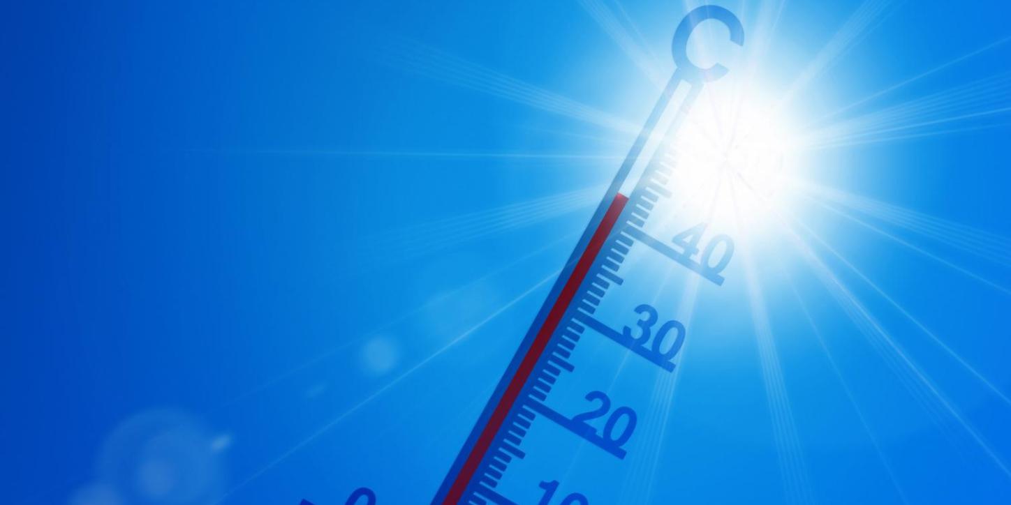Thermometer vor brütend, heißer Sonne und blauem Himmel