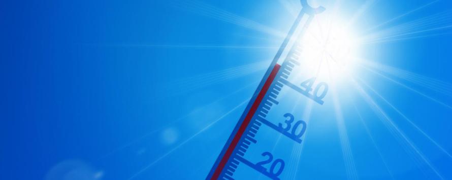 Thermometer vor brütend, heißer Sonne und blauem Himmel