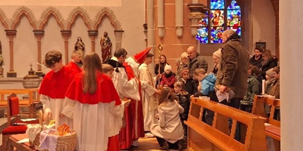 Foto der Aktion'Nikolaus kommt in die Kirche', zu sehen ist das Innere von St. Martin, der Einzug des Nikolaus mit seinem Bischofsstab, dazu Messdiener Eltern und Kinder