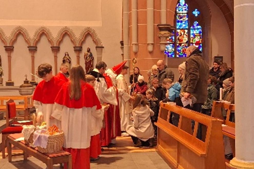 Foto der Aktion'Nikolaus kommt in die Kirche', zu sehen ist das Innere von St. Martin, der Einzug des Nikolaus mit seinem Bischofsstab, dazu Messdiener Eltern und Kinder
