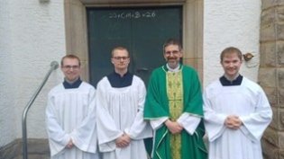 Foto von drei Seminaristen und Pastor Müller vor Seitentür von St. Josef