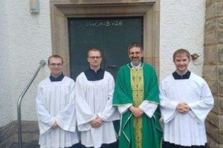 Foto von drei Seminaristen und Pastor Müller vor Seitentür von St. Josef