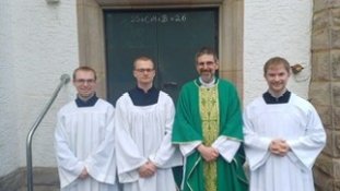Foto von drei Seminaristen und Pastor Müller vor Seitentür von St. Josef
