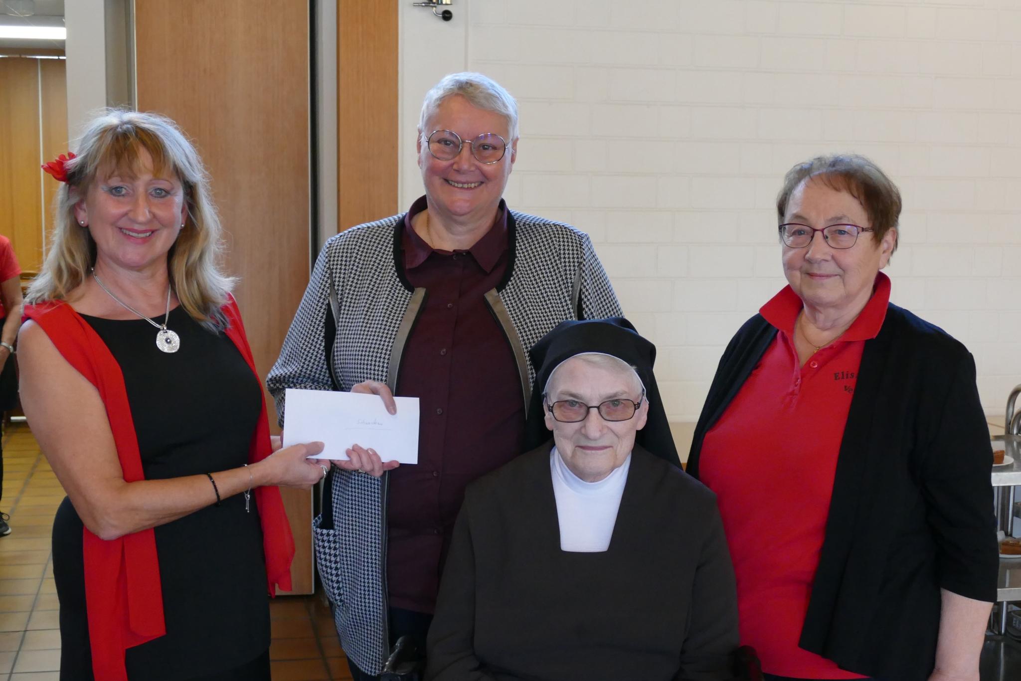 Foto der Spendenübergabe des EV St. Josef für Malawi, vier Personen, eine hält einen symbolischen Scheck in der Hand