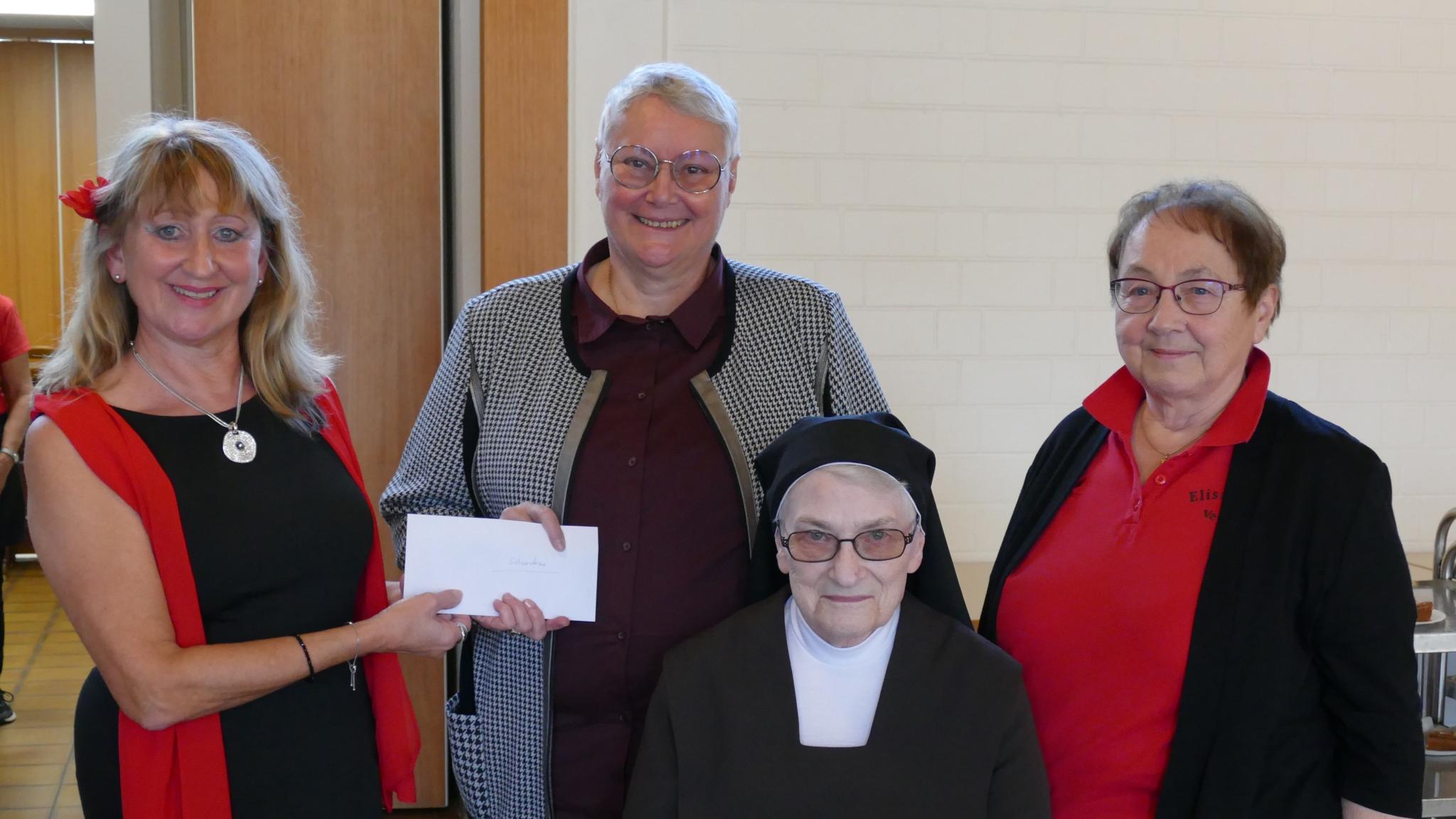 Foto der Spendenübergabe des EV St. Josef für Malawi, vier Personen, eine hält einen symbolischen Scheck in der Hand